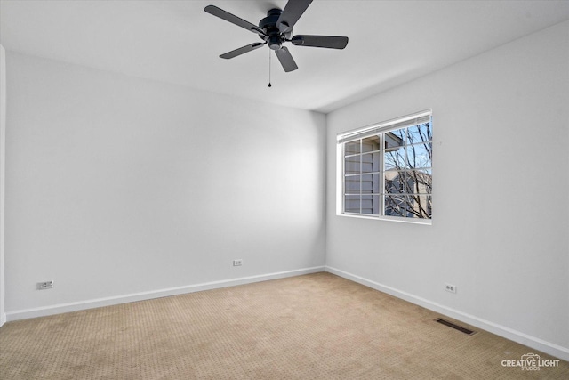 carpeted spare room with baseboards, visible vents, and ceiling fan