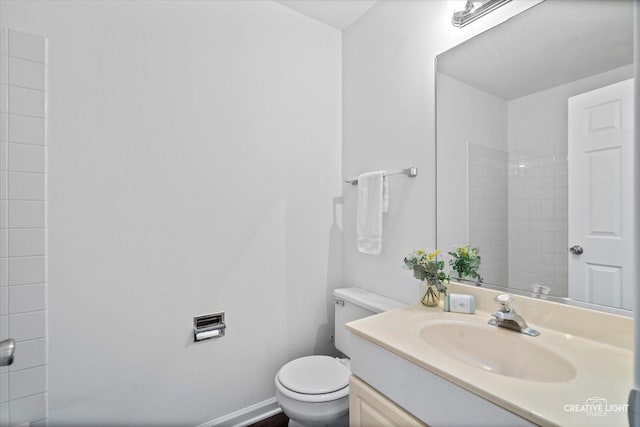 bathroom with toilet, vanity, and baseboards