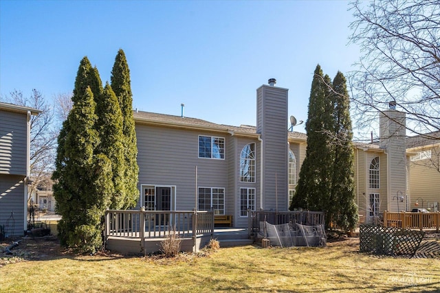 back of property featuring a yard, a chimney, and a wooden deck