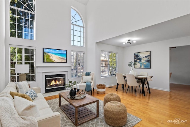 living area featuring a fireplace with flush hearth, wood finished floors, and baseboards