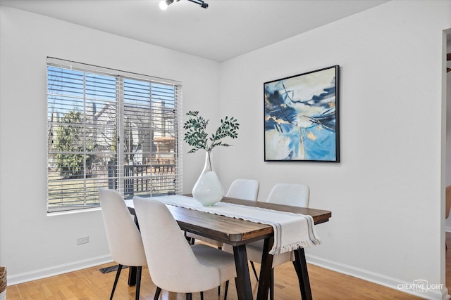 dining space featuring light wood-style flooring and baseboards