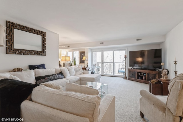 living area with visible vents and light carpet