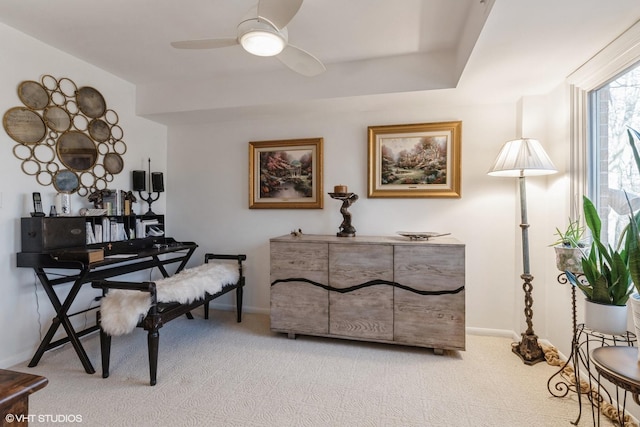 living area with baseboards, light carpet, and a ceiling fan