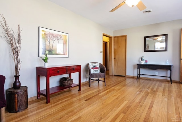 living area with light wood-type flooring, visible vents, ceiling fan, and baseboards