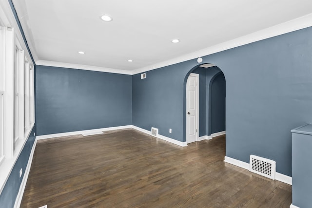 unfurnished room with arched walkways, recessed lighting, wood finished floors, visible vents, and baseboards