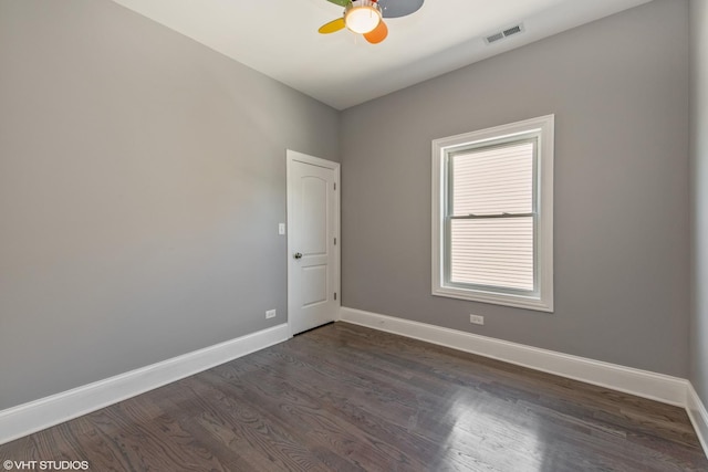 unfurnished room featuring a ceiling fan, dark wood-style flooring, visible vents, and baseboards