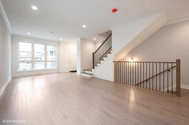 unfurnished living room with crown molding, recessed lighting, wood finished floors, baseboards, and stairs