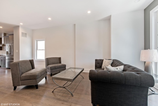 living area featuring recessed lighting, visible vents, baseboards, and wood finished floors