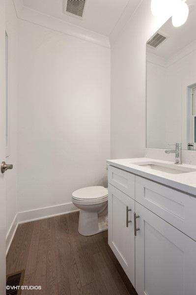 bathroom featuring visible vents, crown molding, vanity, and wood finished floors