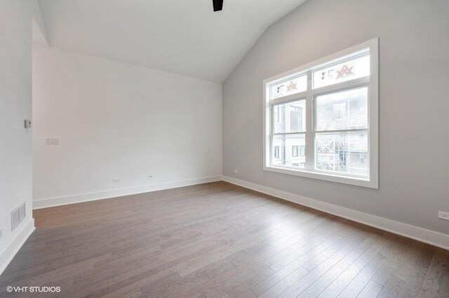 empty room featuring visible vents, vaulted ceiling, baseboards, and wood finished floors