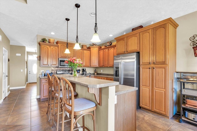 kitchen with a center island, a kitchen breakfast bar, stainless steel appliances, and a textured ceiling