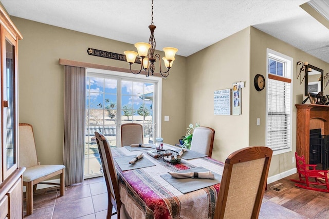 dining space featuring a textured ceiling, visible vents, baseboards, and a chandelier