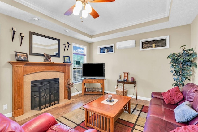 living area featuring a tray ceiling, crown molding, wood finished floors, and a wall mounted air conditioner