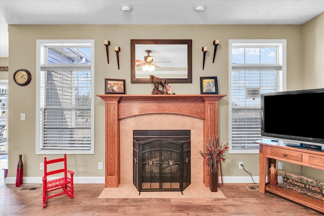 living room featuring visible vents, baseboards, a textured ceiling, and a tile fireplace