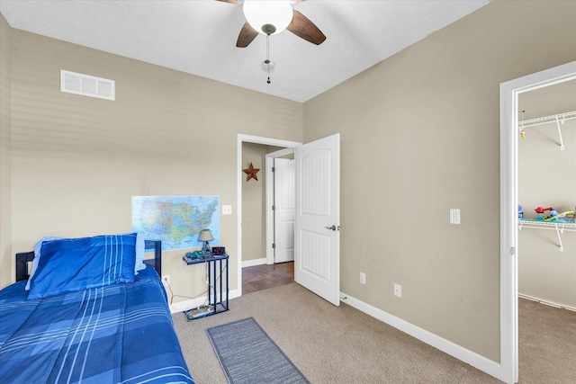 carpeted bedroom with visible vents, baseboards, ceiling fan, and a spacious closet