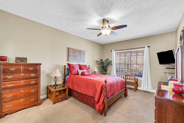 bedroom with light carpet, baseboards, a textured ceiling, and a ceiling fan