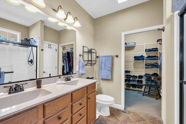 bathroom with a sink, toilet, a stall shower, and double vanity