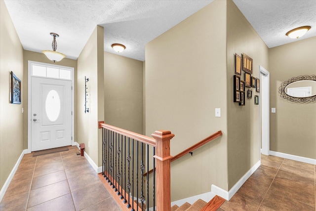 entryway featuring tile patterned flooring, a textured ceiling, and baseboards