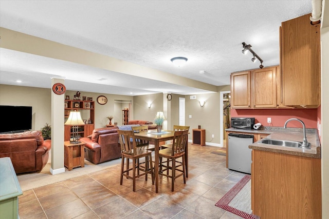 kitchen featuring dishwashing machine, baseboards, a sink, a textured ceiling, and open floor plan