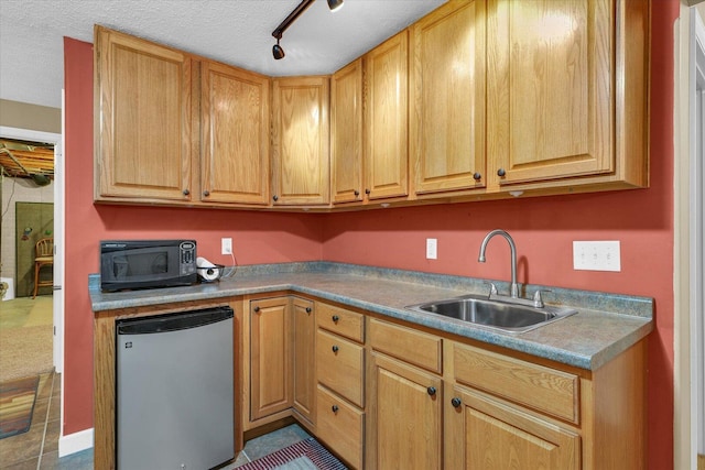 kitchen with a sink, track lighting, black microwave, a textured ceiling, and fridge