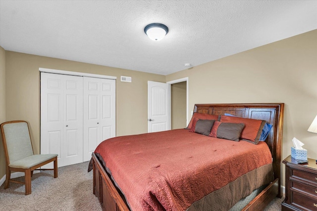 bedroom featuring a closet, visible vents, a textured ceiling, and light carpet