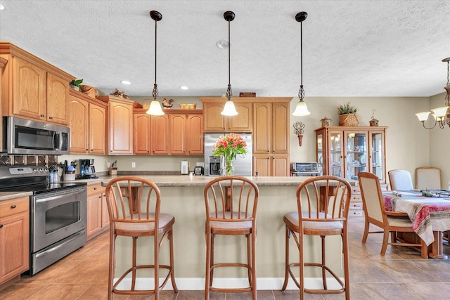 kitchen with a kitchen island, a breakfast bar, stainless steel appliances, hanging light fixtures, and light countertops