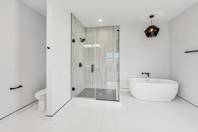 bathroom featuring tile patterned flooring, a shower stall, a freestanding tub, and toilet