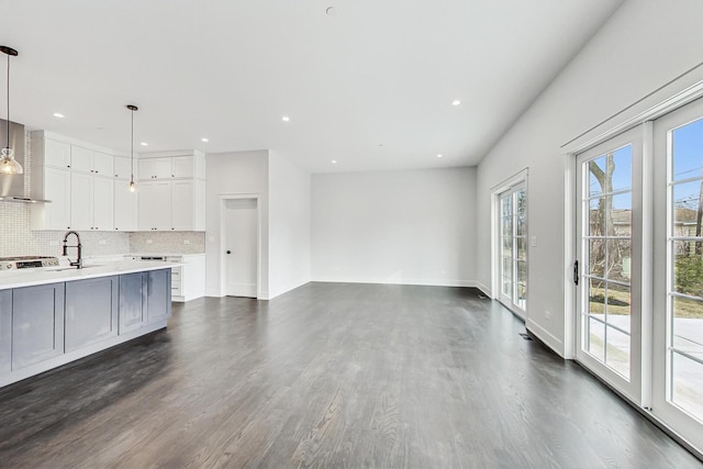 unfurnished living room featuring recessed lighting, baseboards, dark wood finished floors, and a sink