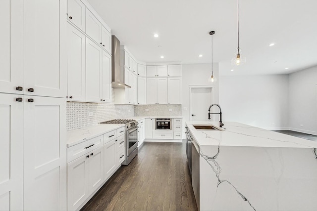 kitchen featuring tasteful backsplash, a sink, wall chimney range hood, stainless steel gas range, and dark wood-style flooring