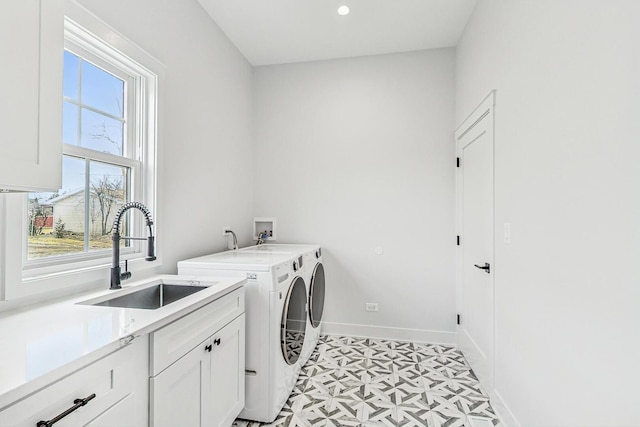 clothes washing area featuring a sink, washing machine and dryer, cabinet space, baseboards, and light floors