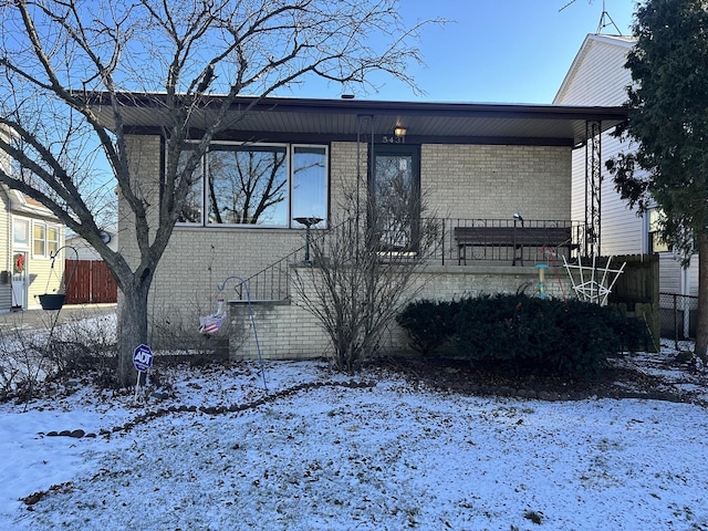 snow covered property featuring brick siding