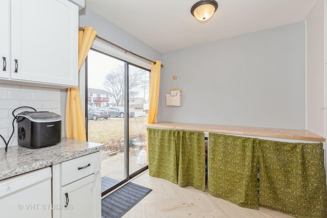 kitchen featuring white dishwasher, white cabinetry, and decorative backsplash