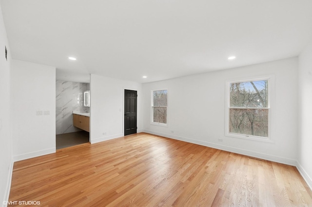 unfurnished bedroom featuring light wood-style floors, ensuite bath, baseboards, and recessed lighting