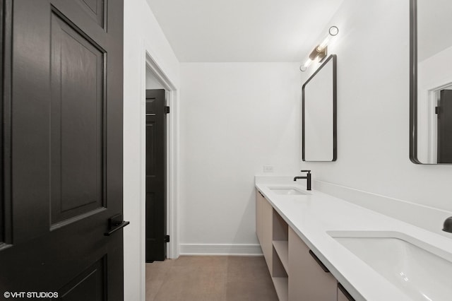 full bath with double vanity, baseboards, and a sink