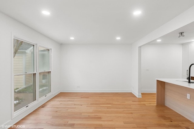 interior space featuring light wood finished floors, baseboards, a sink, and recessed lighting