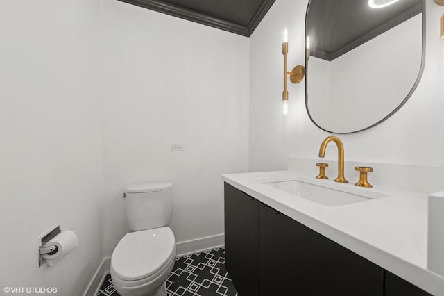 bathroom featuring toilet, baseboards, crown molding, and vanity