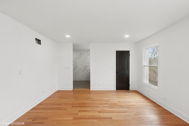 spare room featuring recessed lighting, light wood-type flooring, and baseboards