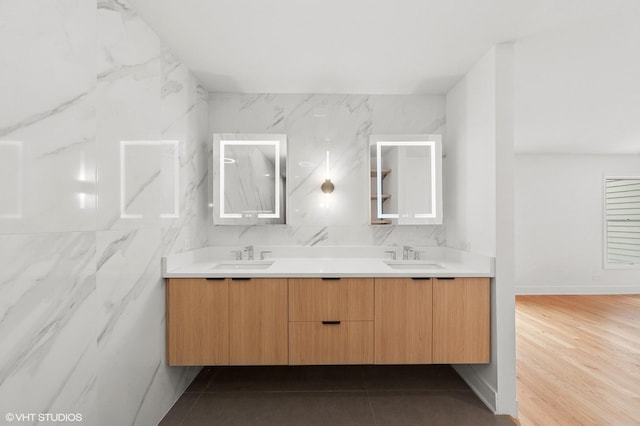 full bathroom featuring wood finished floors, a sink, backsplash, and double vanity