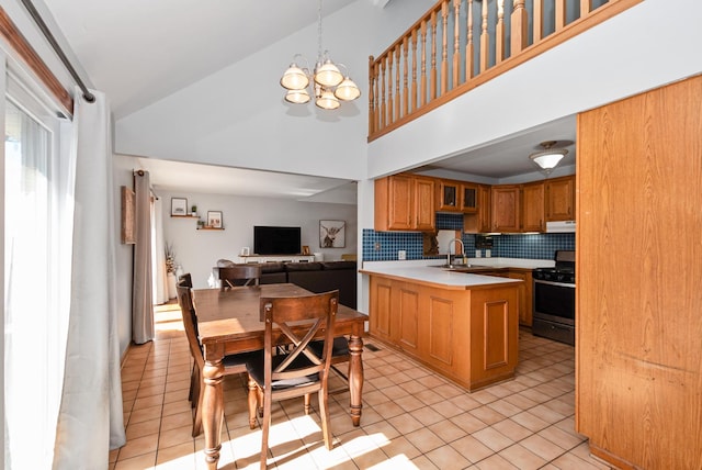 kitchen featuring under cabinet range hood, light tile patterned floors, range with gas stovetop, decorative backsplash, and a sink