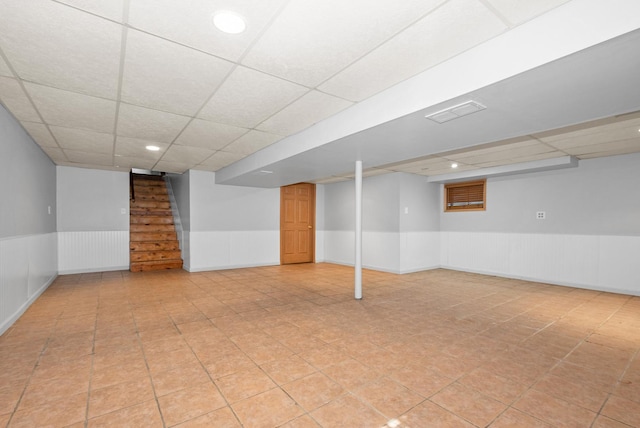 finished basement with stairway, recessed lighting, a paneled ceiling, and a wainscoted wall