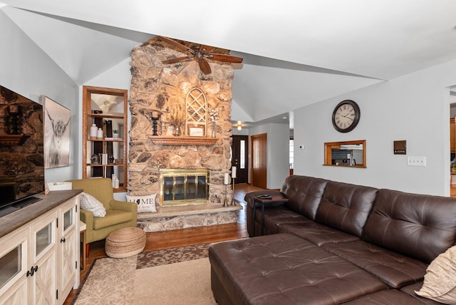 living room featuring wood finished floors, lofted ceiling, a stone fireplace, and ceiling fan