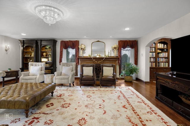 living room with arched walkways, wood finished floors, a fireplace, a chandelier, and recessed lighting