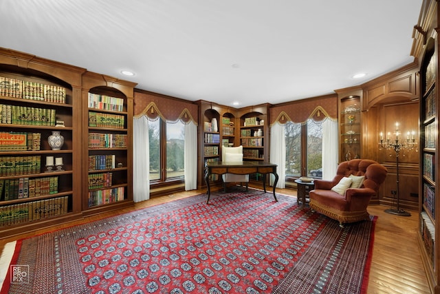 sitting room with a healthy amount of sunlight, built in features, and wood finished floors