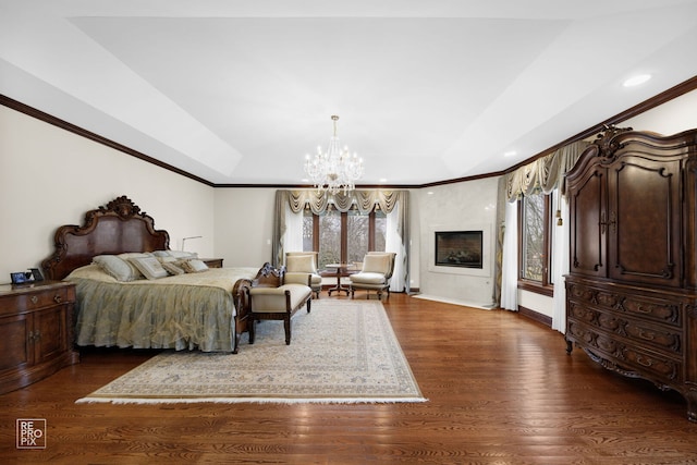 bedroom featuring a fireplace, multiple windows, dark wood finished floors, and a raised ceiling