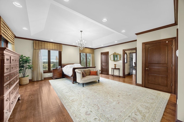 bedroom with a tray ceiling, crown molding, a notable chandelier, recessed lighting, and wood finished floors