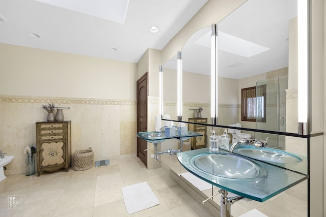 bathroom featuring a skylight, wainscoting, tile walls, and tile patterned floors