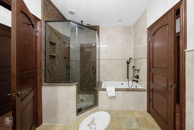 bathroom featuring a stall shower and a bath