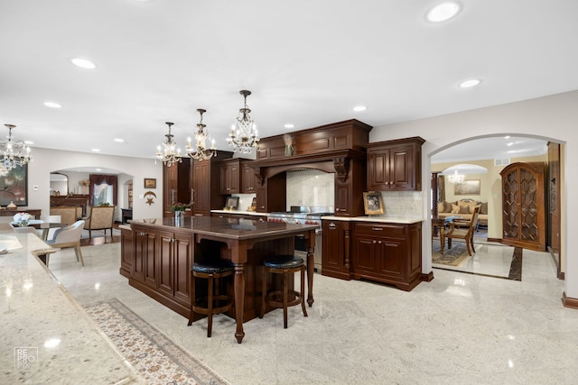 kitchen featuring arched walkways, high end range, hanging light fixtures, backsplash, and recessed lighting