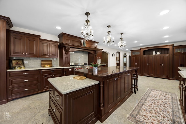 kitchen with arched walkways, tasteful backsplash, a kitchen island, and recessed lighting