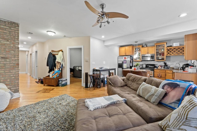 living room featuring light wood-type flooring, a ceiling fan, and recessed lighting